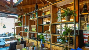 A restaurant with wooden shelves and tables, featuring various items like plants and kitchenware. - Cheerful Mobile Home Near Park De Veluwe (Otterlo)