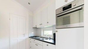 Una cocina con armarios blancos, una estufa, un fregadero y un ventanal.