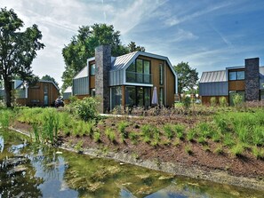 A modern house with a large glass window, a chimney, and a small pond in front. - Modern With Dishwasher, 6km From Elburg (Biddinghuizen)