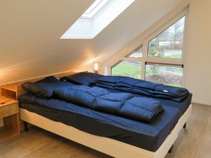 A bedroom with a skylight, a bed with dark bedding, a bedside table, and a view of the outdoors. - Modern With Dishwasher, 6km From Elburg (Biddinghuizen)