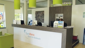 A reception desk at EuroParcs with a sign reading "Resort De Biesbosch." There are green chairs, a computer, and a shelf with brochures. - Well-kept Chalet Near the Biesbosch (Dordrecht)