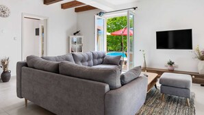 Uma sala de estar moderna com um sofá seccional cinza, uma mesa de centro de madeira e uma televisão de tela plana fixada na parede.