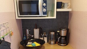 Een functionele keuken met een magnetron, koffiezetapparaat en een kleine koelkast.