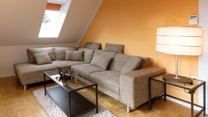 A modern living room with a sectional sofa, a glass coffee table, a floor lamp, and a small side table.