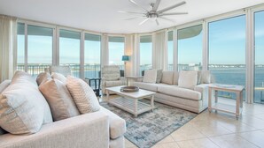 A spacious living room with a large window, a ceiling fan, and a view of the water.