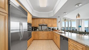 A modern kitchen with stainless steel appliances, wooden cabinets, and a large island.