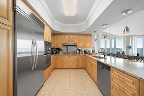 A modern kitchen with stainless steel appliances, wooden cabinets, and a large island.