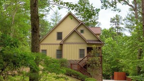 A two-story house with a stone foundation, a wooden staircase, and a concrete pathway leading to the front door. - Retreat 52 - Family retreat / Innsbruck GolfResort (Helen)