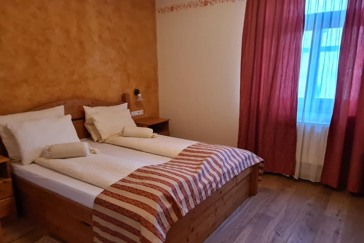 Un lit bien fait, avec du linge de lit blanc et une couverture à rayures, une tête de lit en bois et une table de chevet avec une lampe.
