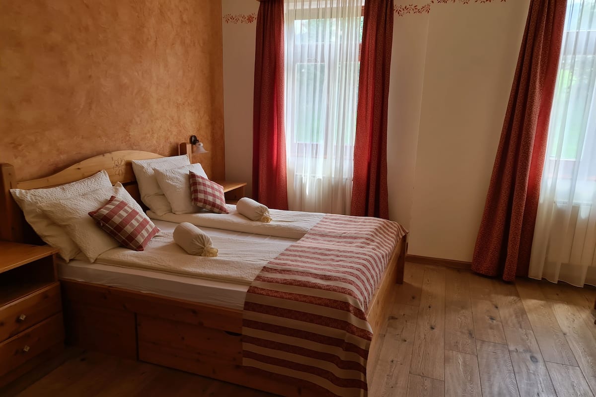 Un lit bien fait, avec une couvre-lit à rayures, une tête de lit en bois et plusieurs oreillers.