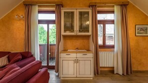 A room with a red sofa, white cabinets, and a window with curtains. - Apartments Sitar (Ribnica na Pohorju)