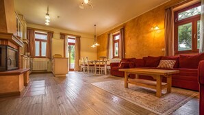 Ein geräumiges Wohnzimmer mit einem roten Sofa, einem Holztisch und einem Essbereich mit Tisch und Stühlen.
