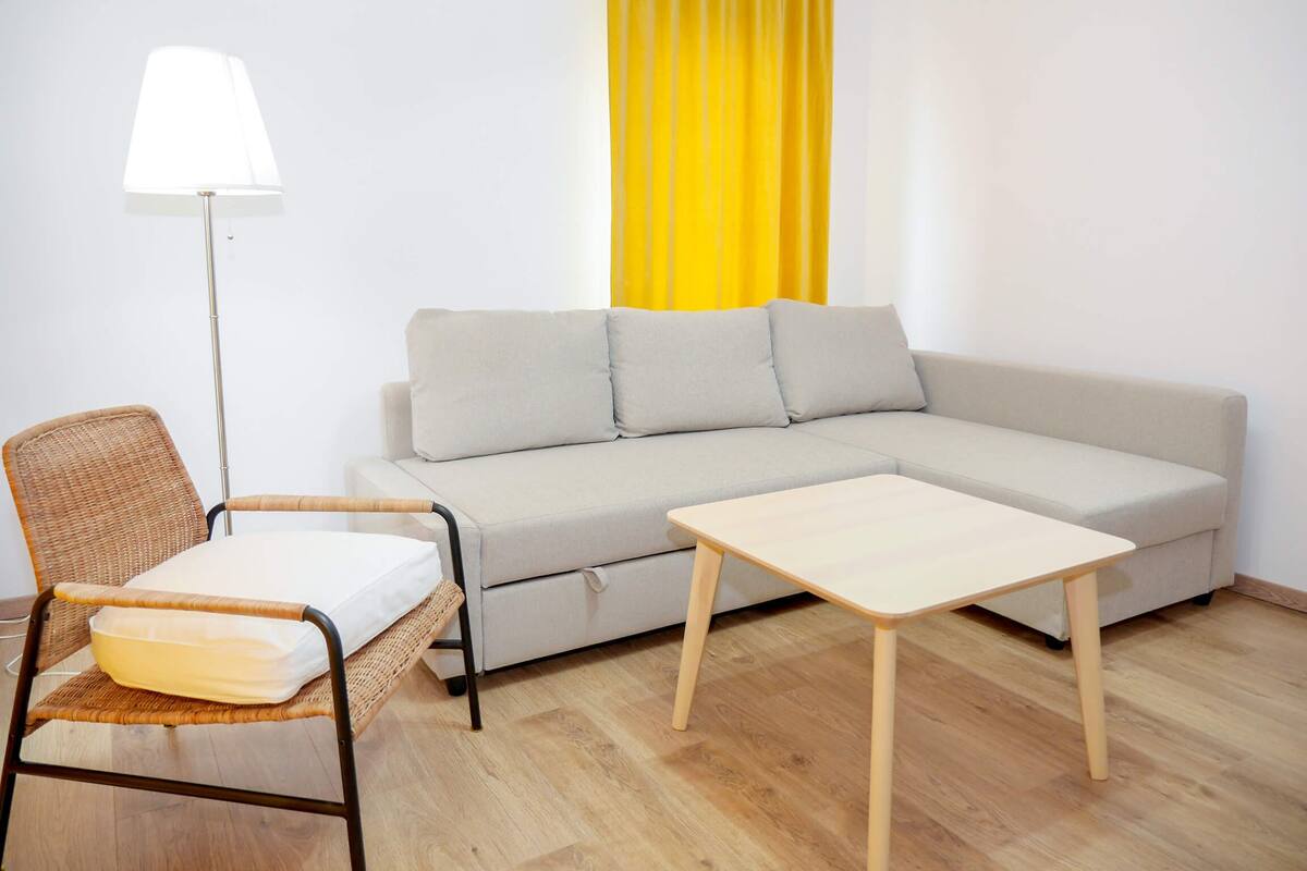 Ein modernes Wohnzimmer mit einer Couch, einem kleinen Tisch, einem Sessel und einer Stehlampe.