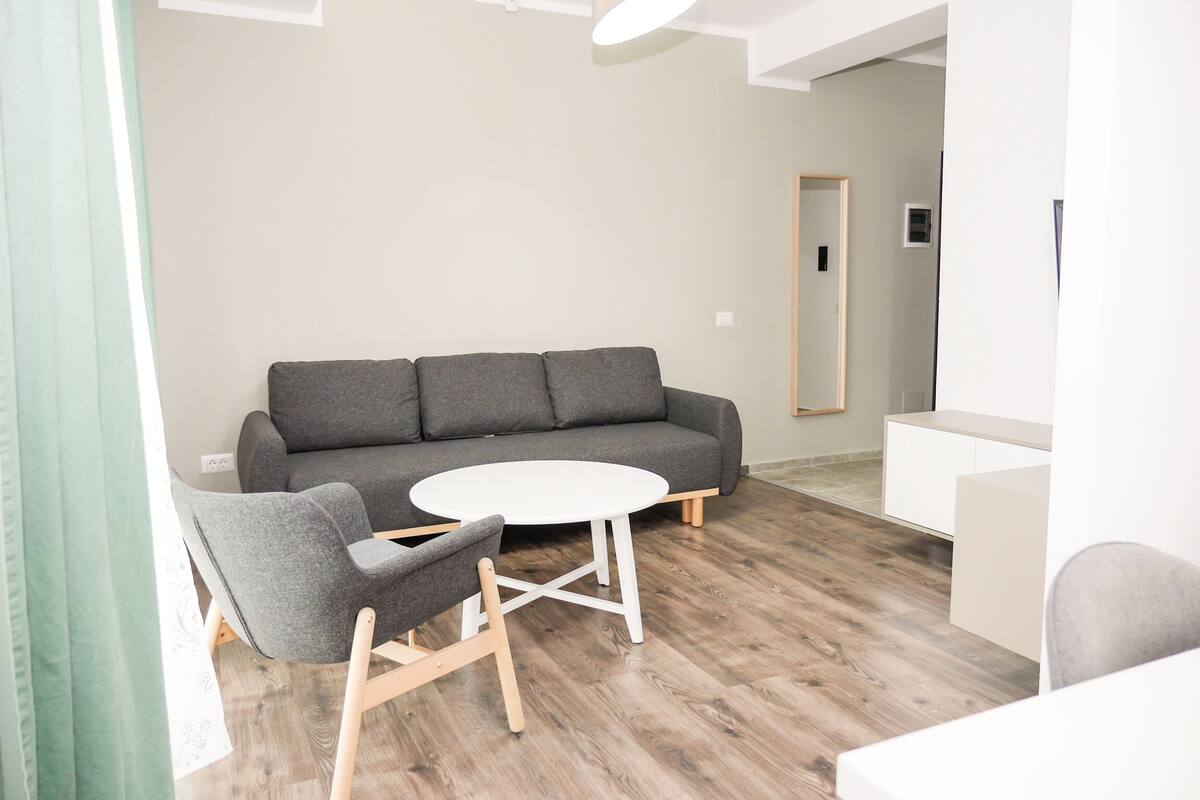 Ein modernes Wohnzimmer mit grauem Sofa, einem weißen Couchtisch und einem grauen Sessel.