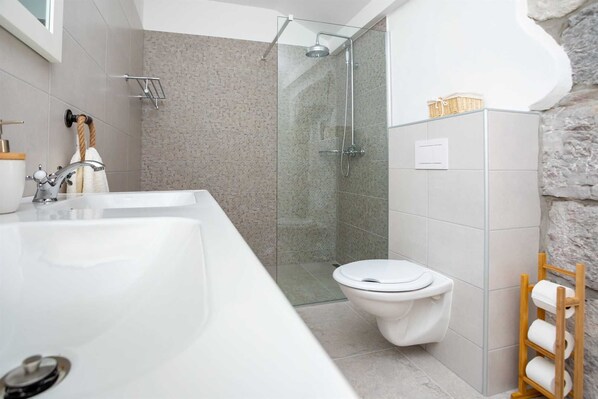 Un baño moderno con una bañera blanca grande, una zona de ducha separada y un inodoro.