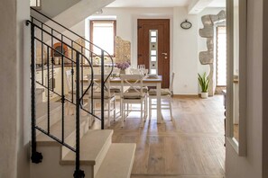 Una escalera conduce a un comedor con una mesa de madera dispuesta para una comida, una planta en maceta y un revestimiento de pared de piedra.