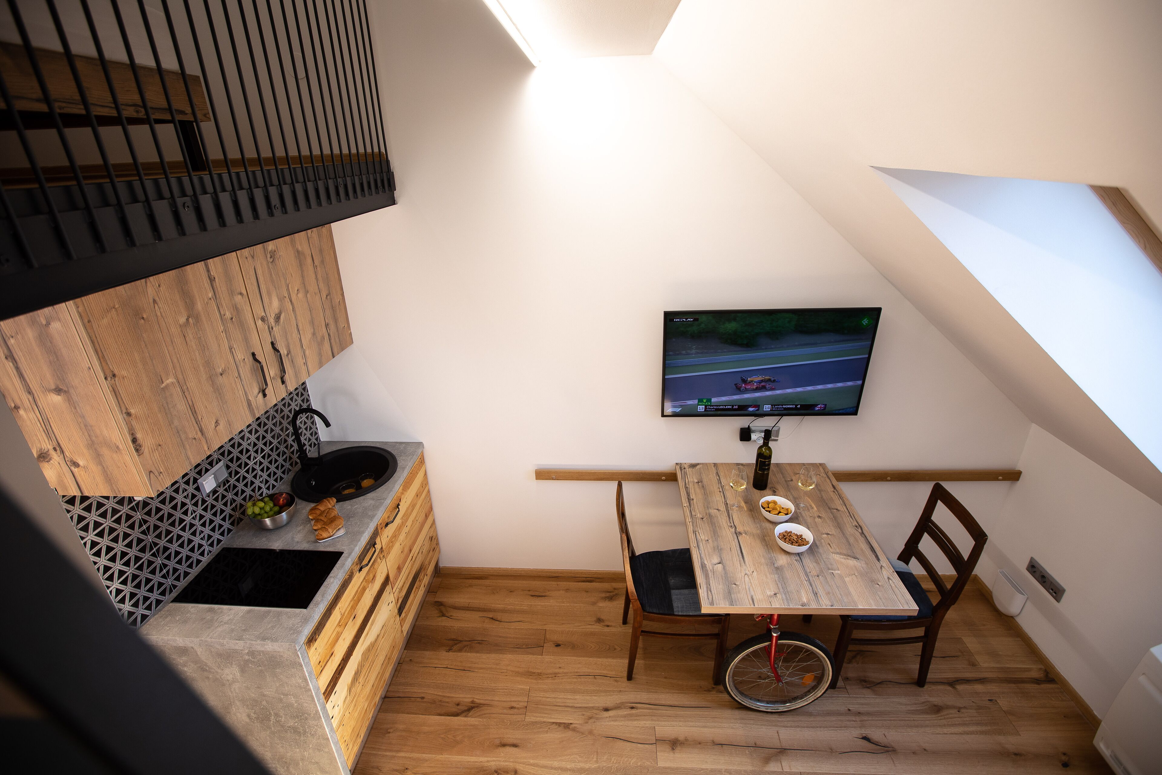 Una cucina compatta con un tavolo da pranzo in legno, una televisione a parete e una bicicletta nell'angolo.