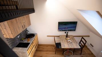 Una cucina compatta con un tavolo da pranzo in legno, una televisione a parete e una bicicletta nell'angolo.