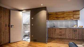 A modern kitchen with wooden cabinets, a tiled backsplash, and a wooden floor.