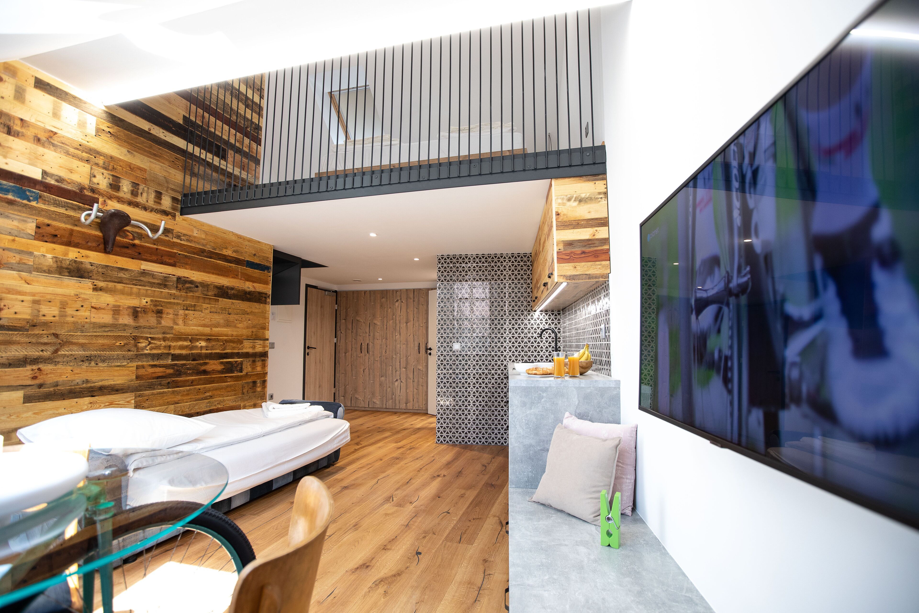 Ein modernes Interieur mit einem Schlafsofa im Loft-Stil, Holzwänden, einer Küchenzeile und einem großen Fernsehbildschirm.