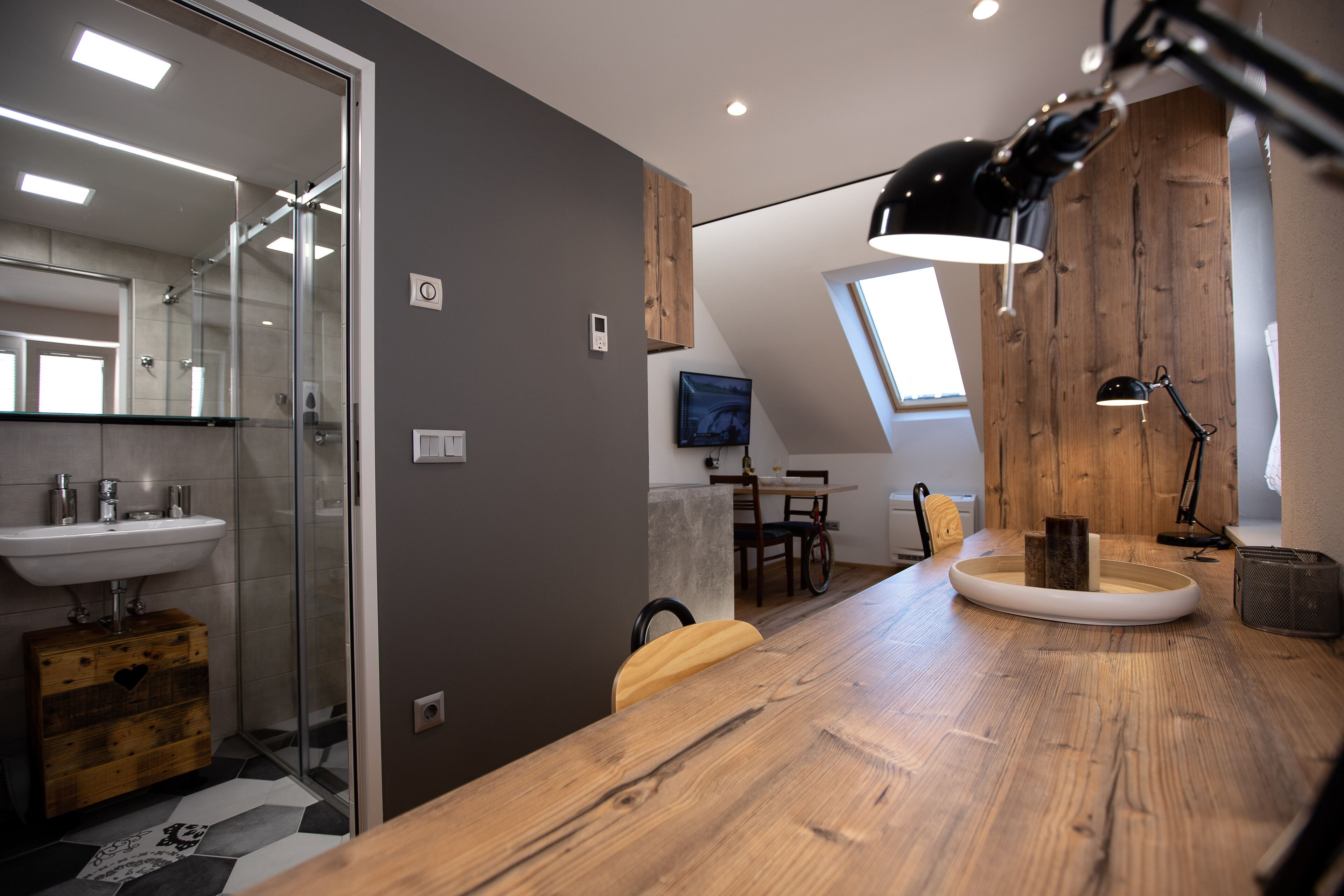 Un baño moderno con ducha de vidrio, tocador de madera y un comedor con mesa y sillas.