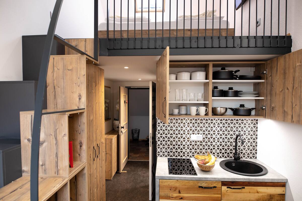 Une cuisine compacte avec des meubles en bois, une cuisinière encastrée et un dosseret carrelé.