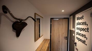A hallway with a wooden bench, a wall-mounted mirror, and a door with a motivational quote.