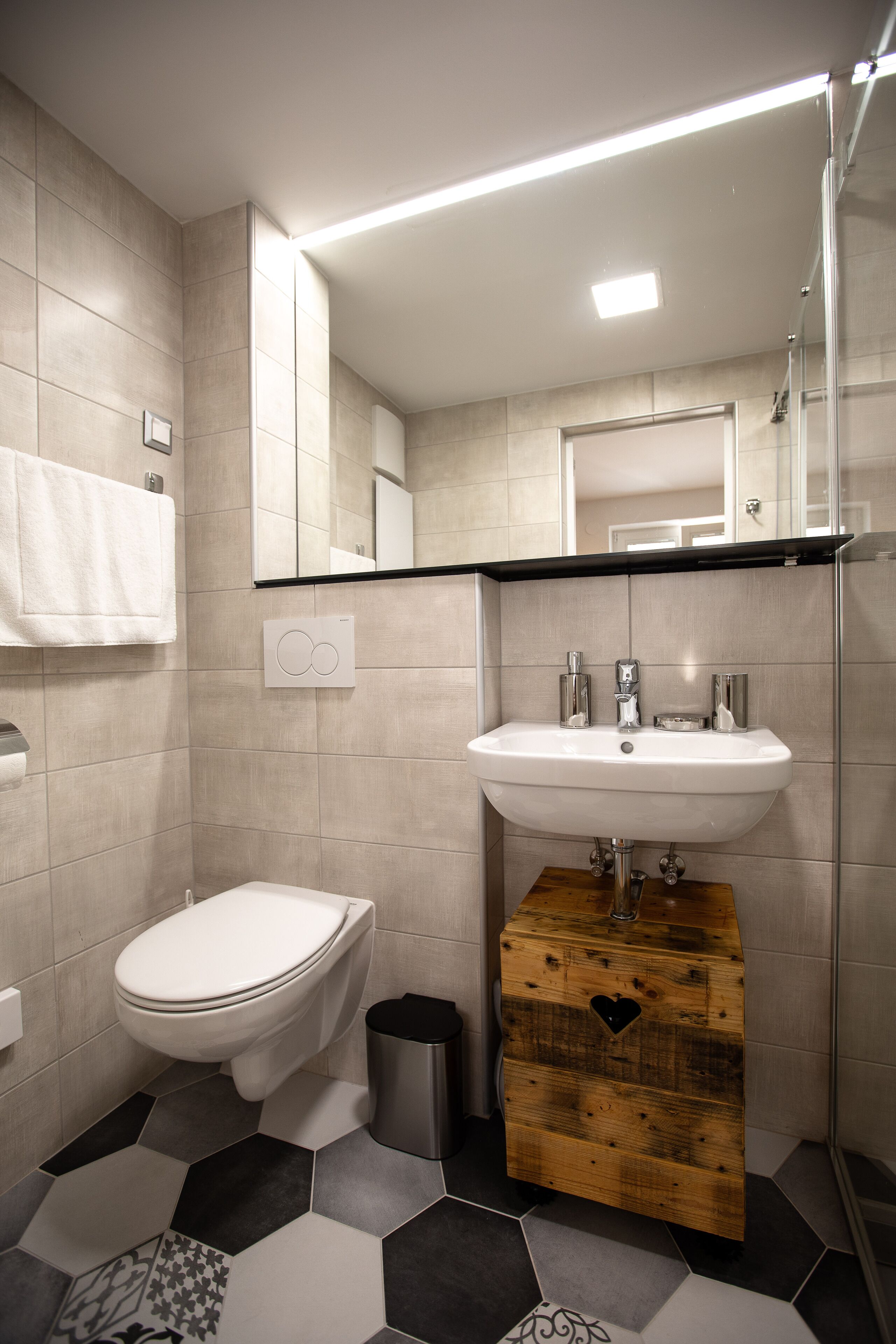 A modern bathroom with a toilet, sink, and mirror.