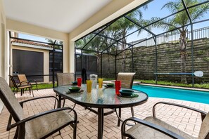 A glass-enclosed patio with a pool, outdoor seating, and a view of palm trees. - Luxury Modern Home With CDC Cleaning Standards, 2 Miles From Disney #6wh546 (Kissimmee)
