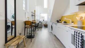 A modern kitchen with a washing machine, a dining area with chairs, and a bench. - Abode Philadelphia - Center City Convention Center (Philadelphia)