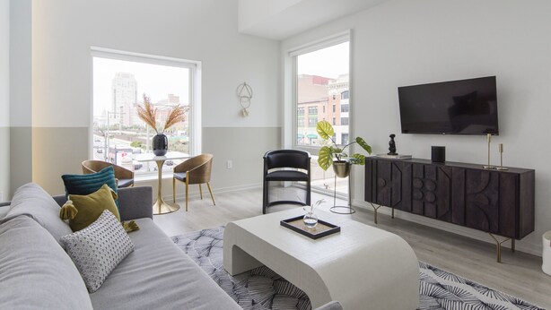 A modern living room with a sofa, a coffee table, a TV, and a dining area with chairs and a table. - Abode Philadelphia - Center City Convention Center (Philadelphia)