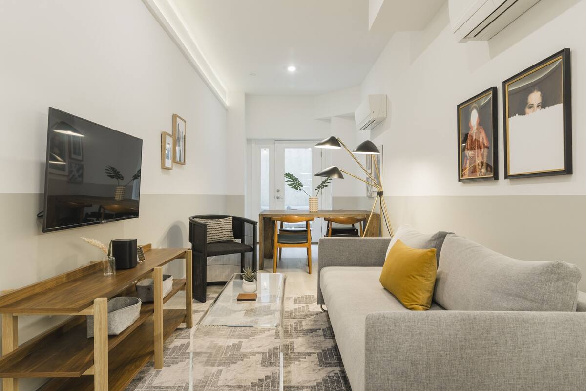 A modern living room with a sofa, coffee table, TV, and artwork on the walls.