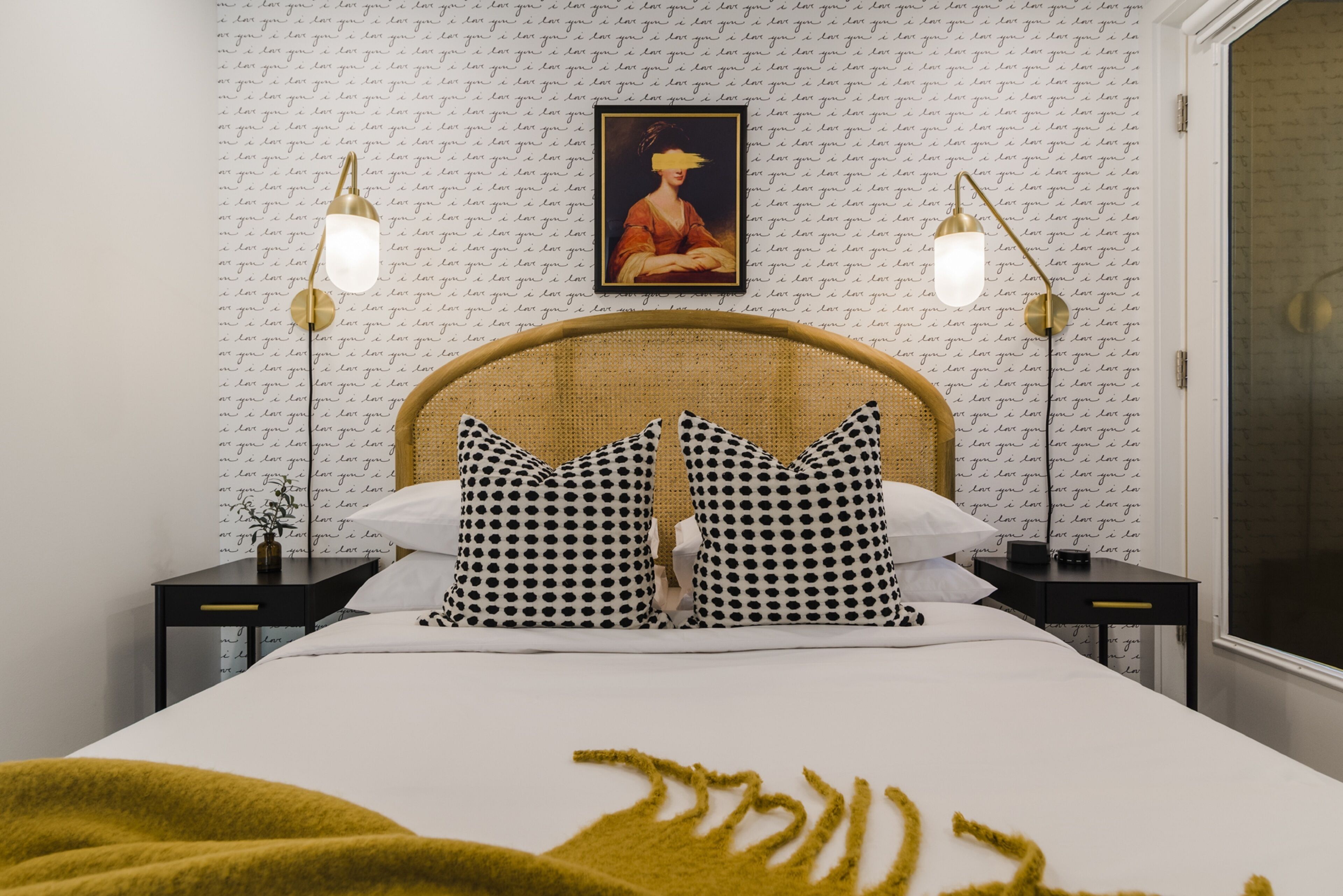 Une chambre à coucher bien aménagée, avec un grand lit, deux tables de chevet, un tableau accroché au mur et deux lampadaires.