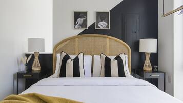 Een netjes ingerichte slaapkamer met een bed, twee nachtkastjes en twee wandlampen.