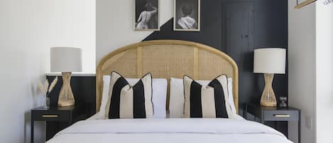Un dormitorio ordenado con una cama, dos mesitas de noche y dos lámparas de pared.