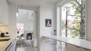 A modern kitchen with a large window, clear stools, and a minimalist design. - Abode Philadelphia - Center City Convention Center (Philadelphia)