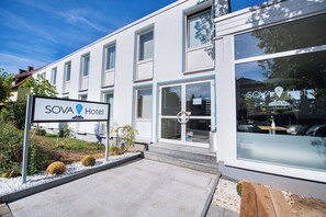 Ett modernt hotell med en skylt där det står ”SOVA Hotel” och en logotyp.