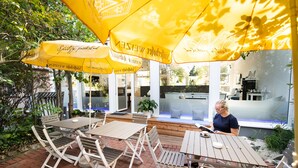 An outdoor seating area with yellow umbrellas, wooden tables, and chairs. - 🏨 SOVA Guesthouse Kassel 🌾 own hotel for up to 18 people (Kassel)