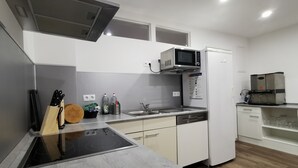 A modern kitchen with a built-in microwave, oven, and dishwasher. There is a wooden cutting board, knives, and a sink. - 🏨 SOVA Guesthouse Kassel 🌾 own hotel for up to 18 people (Kassel)