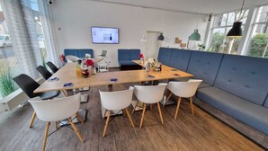 A modern meeting room with a long table, white chairs, a blue sofa, and a computer monitor on the wall. - 🏨 SOVA Guesthouse Kassel 🌾 own hotel for up to 18 people (Kassel)