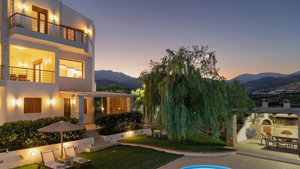 Une maison moderne à deux étages, dotée d’une piscine, d’un espace salon extérieur et d’un grand arbre.