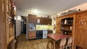 Une cuisine compacte avec des meubles en bois, un four à micro-ondes, un évier et une table à manger avec des chaises.