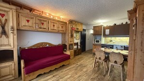 Une pièce chaleureuse, meublée de meubles en bois, avec un canapé rouge et un coin repas comprenant une table et des chaises en bois.