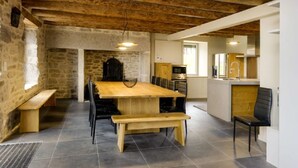 Uma cozinha rústica com mesa e bancos de madeira, paredes de pedra e bancada moderna.