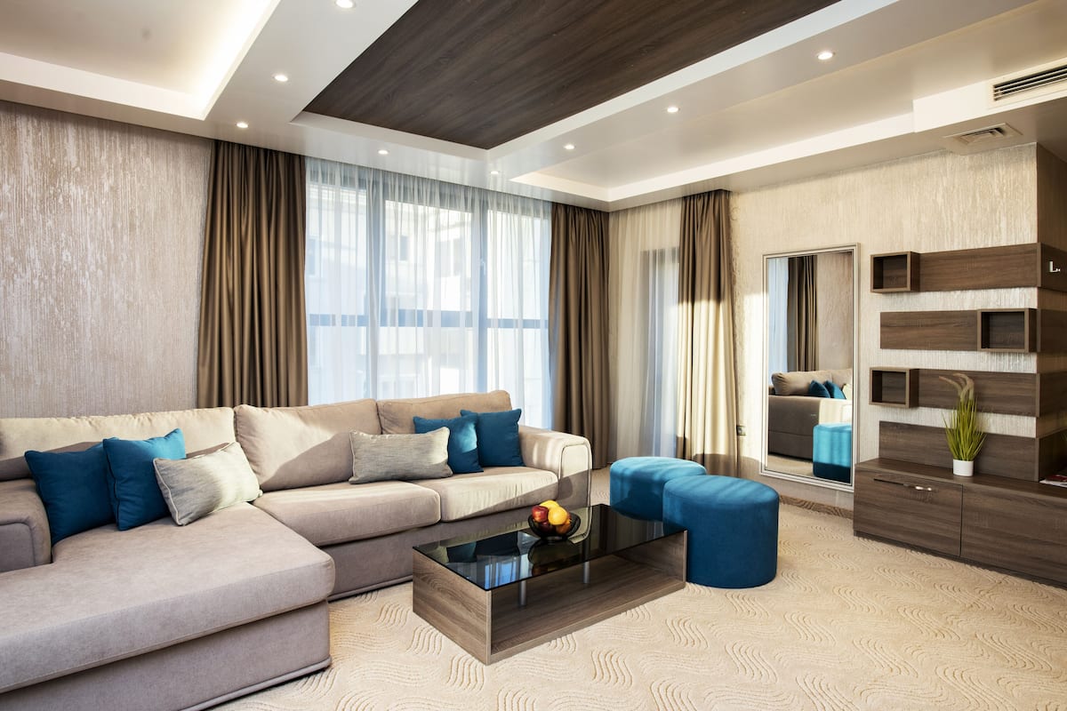 A modern living room with a sectional sofa, a glass coffee table, and a blue ottoman.