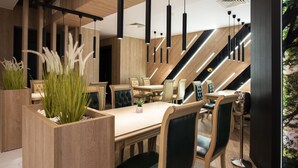 A modern dining area with wooden furniture, pendant lighting, and a view of the outdoors. - Family Hotel Business Club (Shumen)
