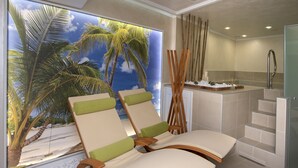 A room with two lounge chairs, a large window with a tropical view, a small kitchen area, and a shower. - Family Hotel Business Club (Shumen)
