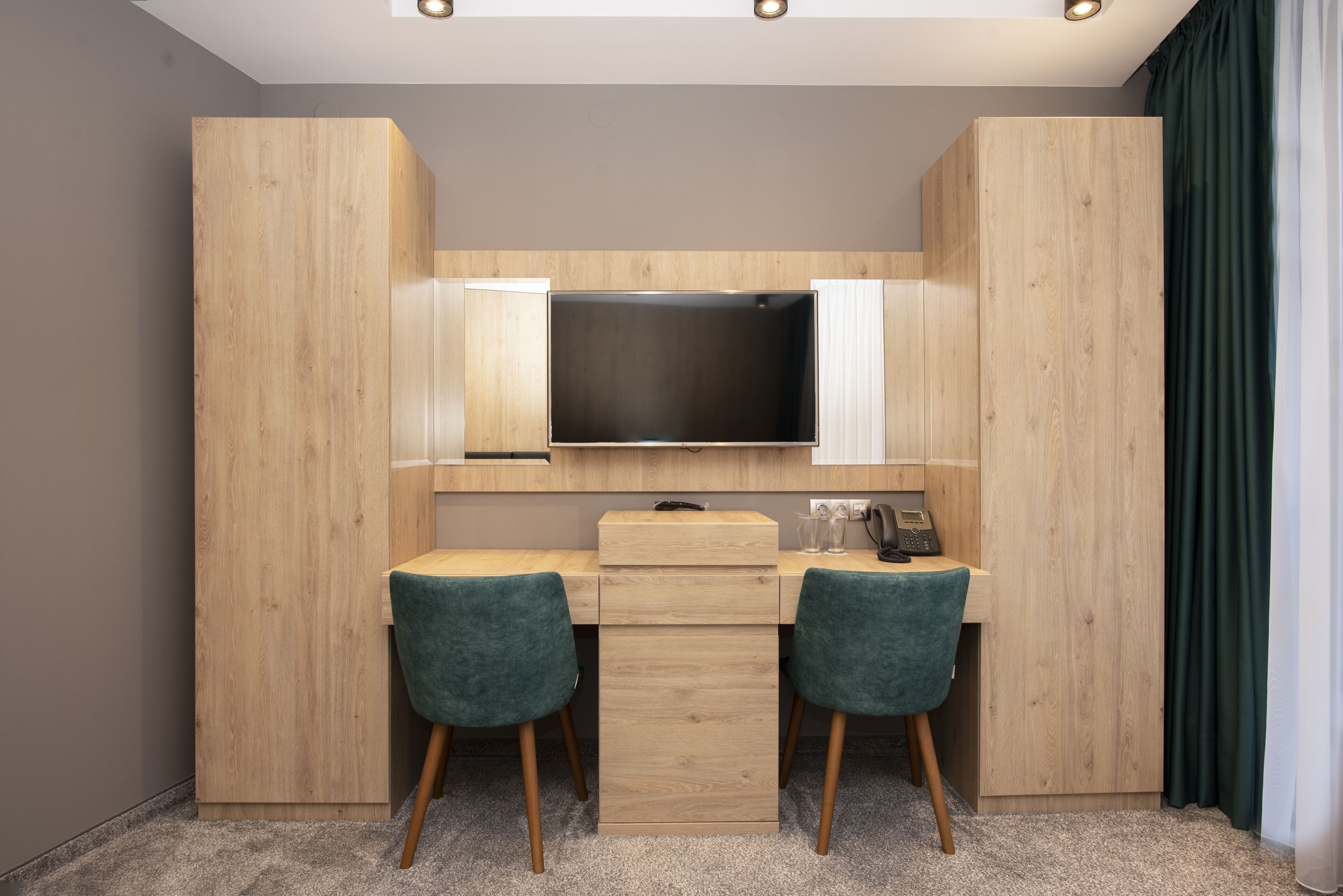 Un espace de travail moderne et compact, équipé d’un téléviseur à écran plat, de deux chaises et d’un bureau doté d’un meuble à tiroirs.