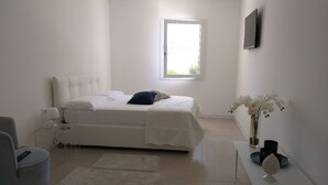 A modern bedroom with a bed, bedside table, chair, and a window. - Villa Flavia, Mediterranean charm. Apartment, private pool at100 mt sea (Fontane Bianche)