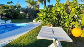 A swimming pool with a white deck, surrounded by lush greenery and palm trees. - Villa Flavia, Mediterranean charm. Apartment, private pool at100 mt sea (Fontane Bianche)